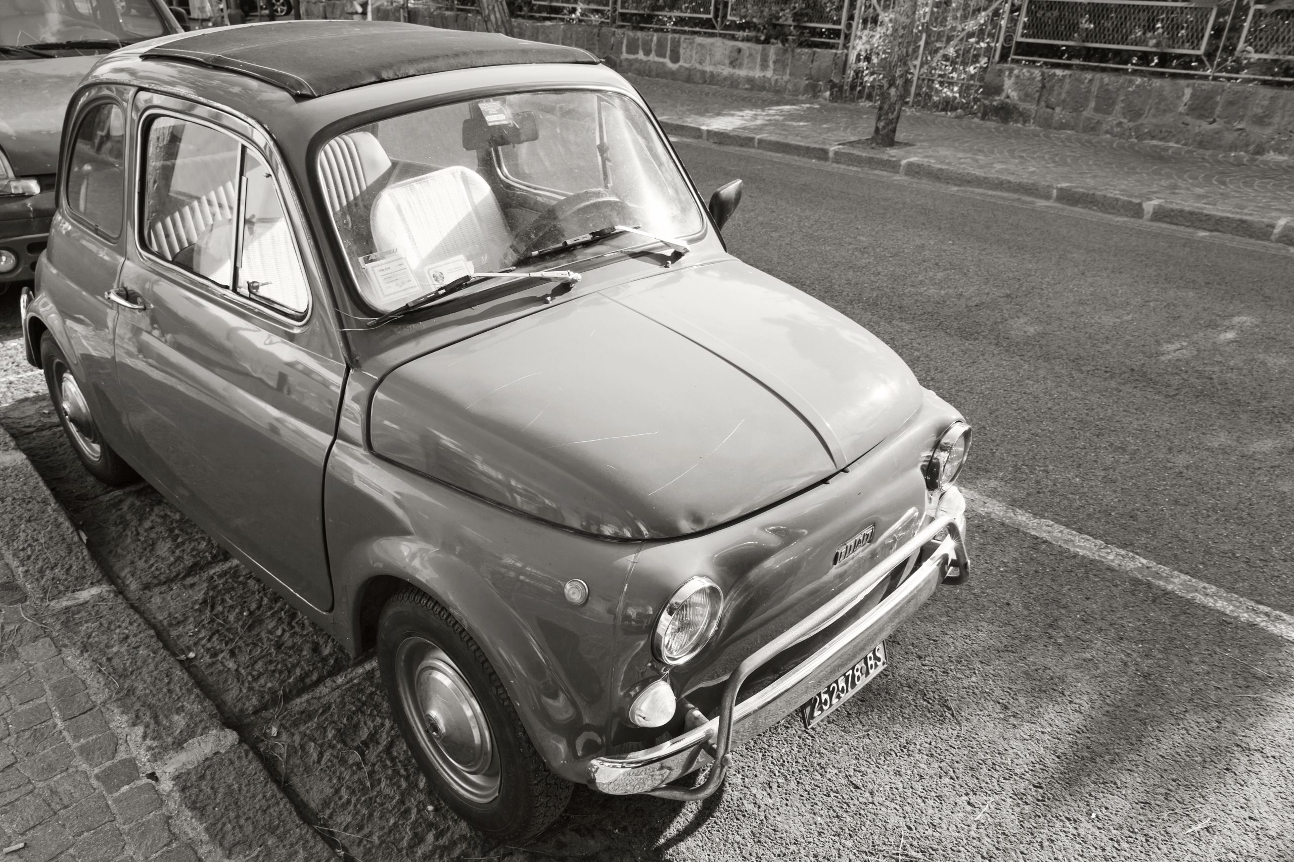 A black and white photograph of a vintage Fiat 500
