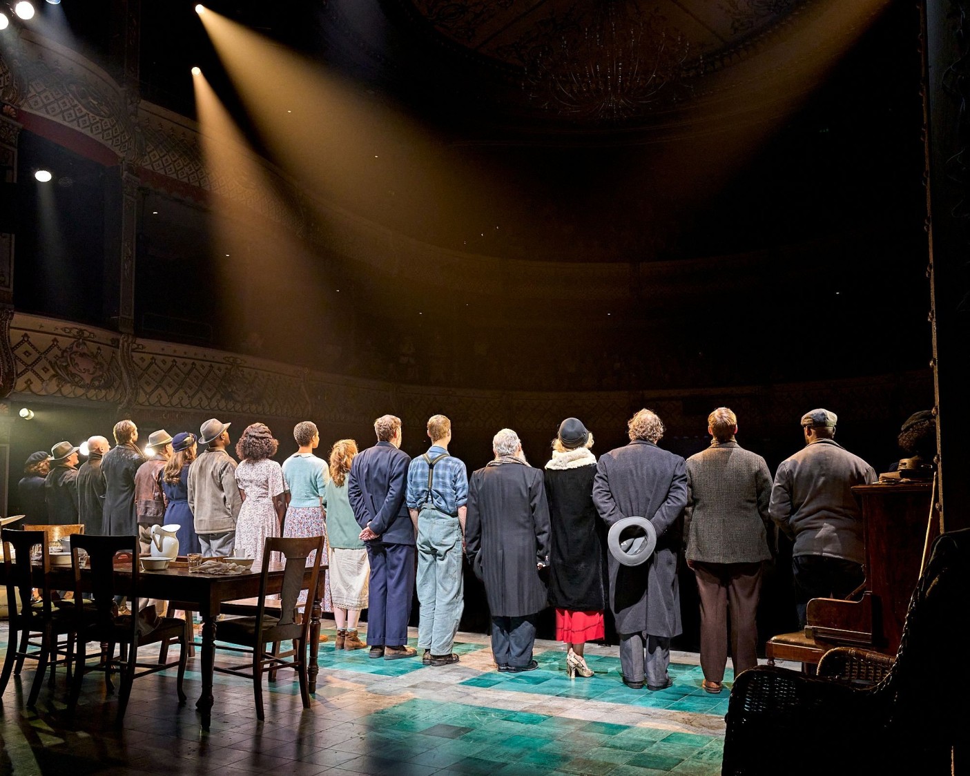 An image of the back of the ensemble taking a bow at the end of the show. They stand in a line facing the audience.