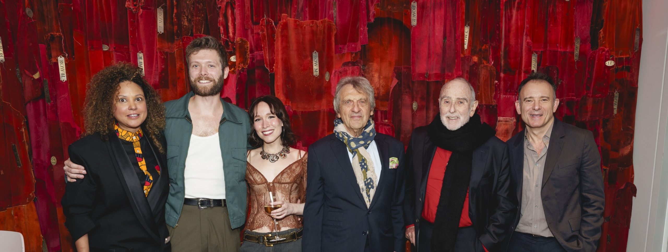 Annabel Mutale Reed, Shane O'Riordan, Liv Andrusier, Alain Boublil, Claude-Michel Schönberg and Matthew Warchus smile as they pose together in front of a wall of red velvet curtains in the foyer of The Old Vic.